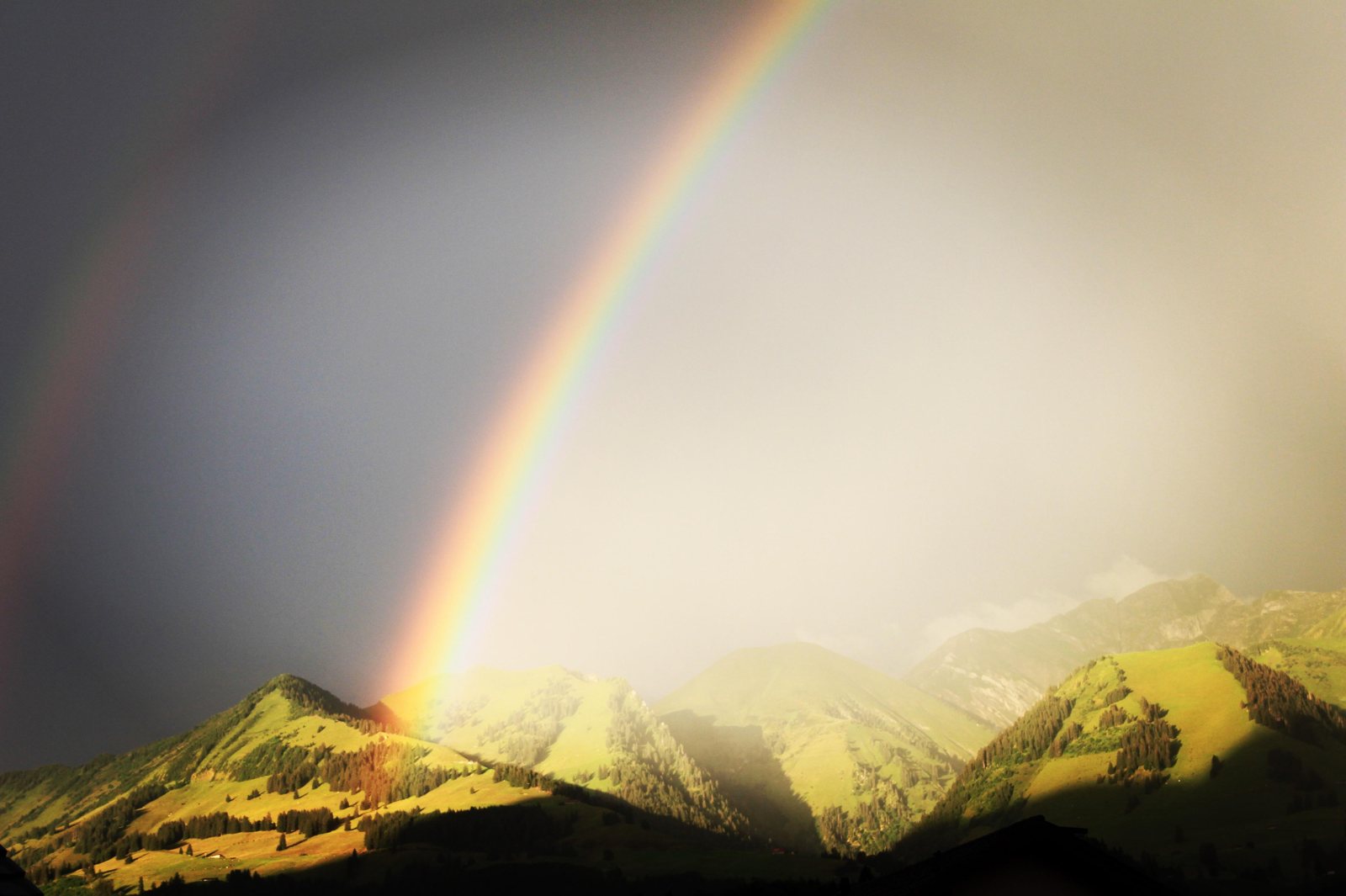 Arc-en-ciel sur les montagnes valaisannes après l'orage, symbole du terrain et des cycles